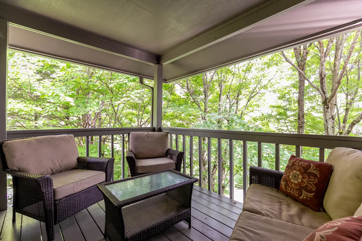 A peaceful seating nook featuring comfortable chairs and a glass-top coffee table, set beside windows revealing surrounding greenery. The calm mood invites guests to enjoy morning coffee while reflecting on their adventures in town.